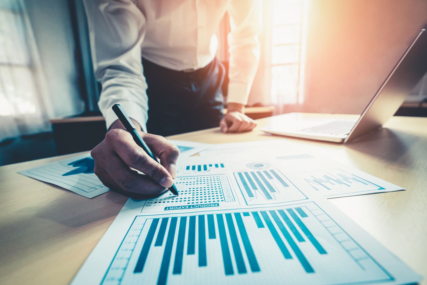 Financial professional reviewing a printed portfolio report by hand at a sunlit desk