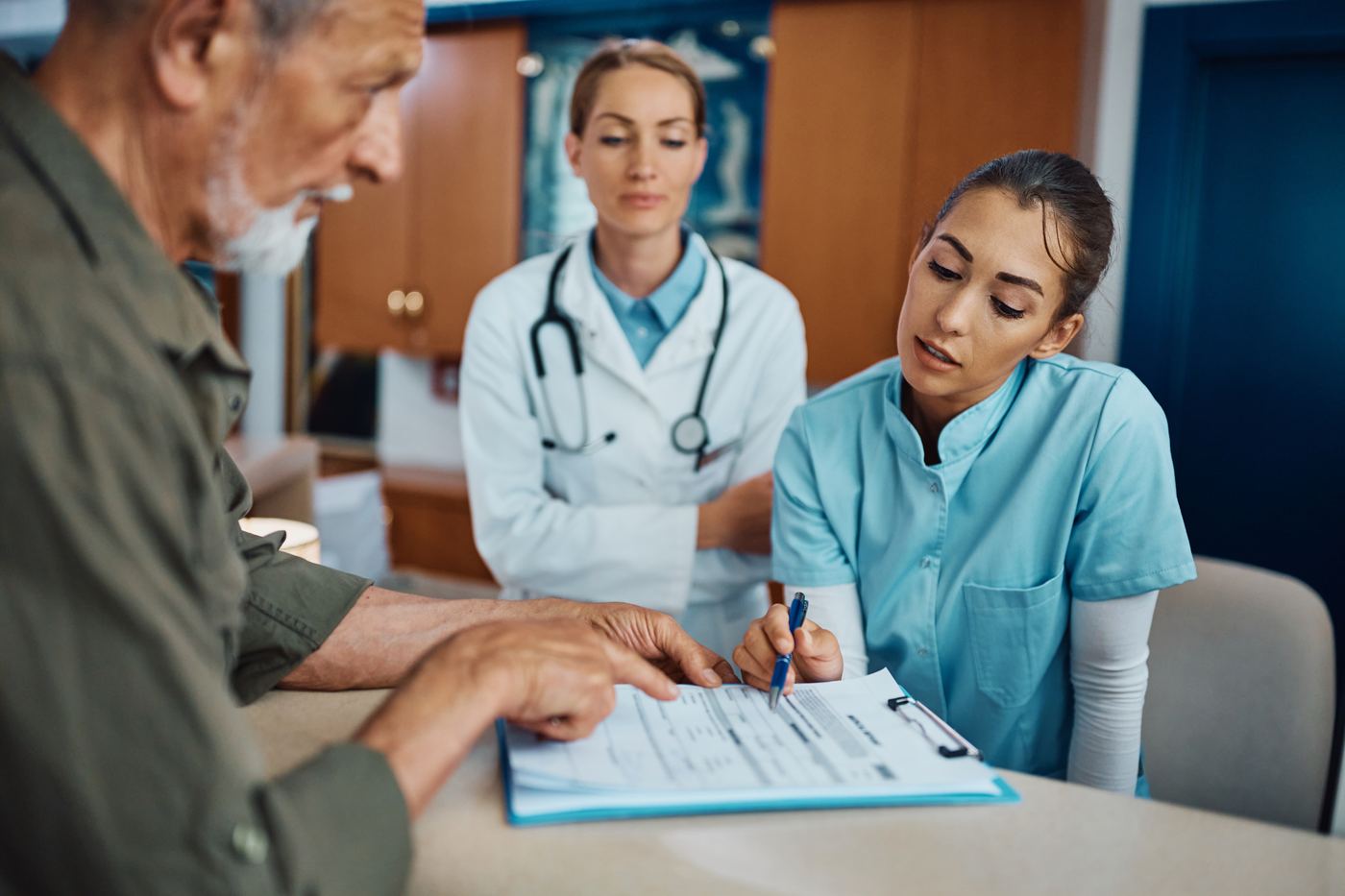 Clinic staff and physician reviewing a patient intake form together at the front desk